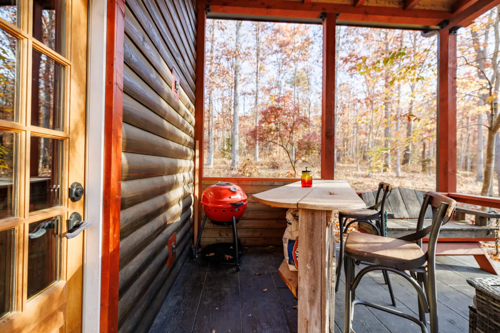 A screened in porch with a table and chairs, located at Little River Point.