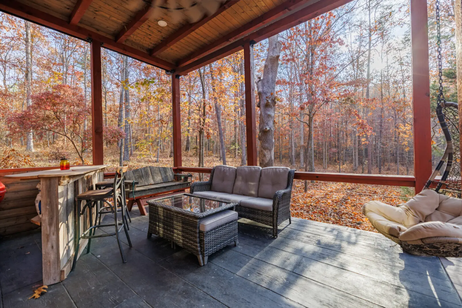 A screened porch with furniture and a fireplace in the fall, located at Little River Point with Sauna.