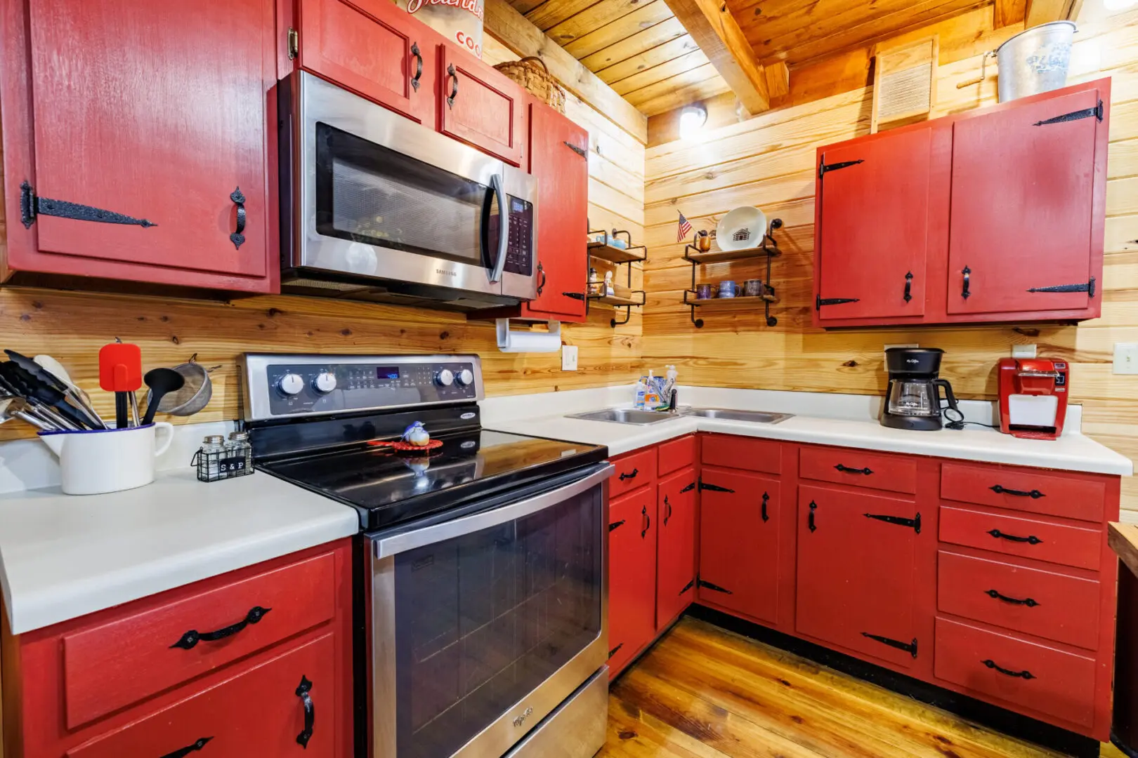A vacation kitchen with red cabinets and stainless steel appliances.