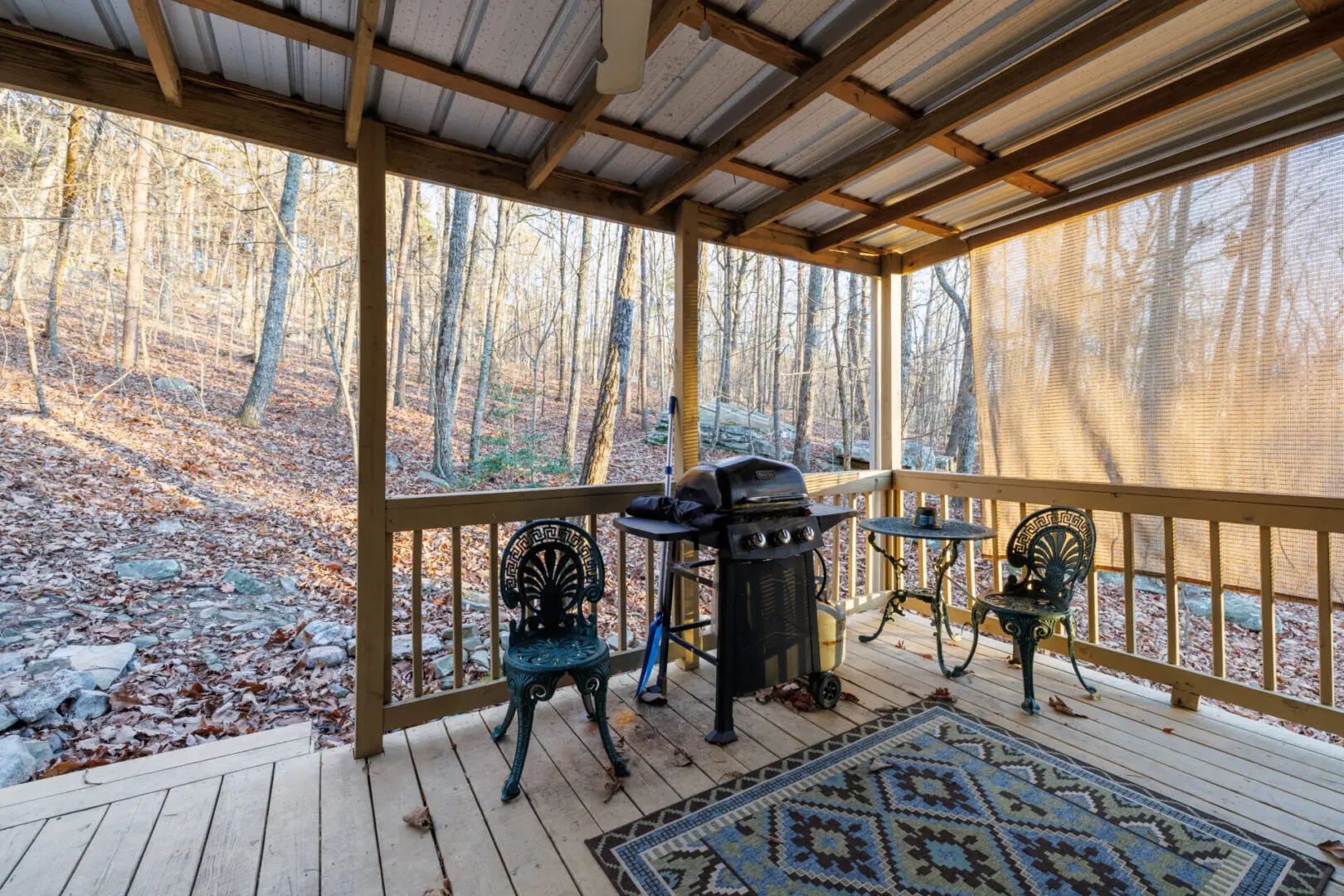 Vacation spot featuring a screened in porch with a grill and chairs.