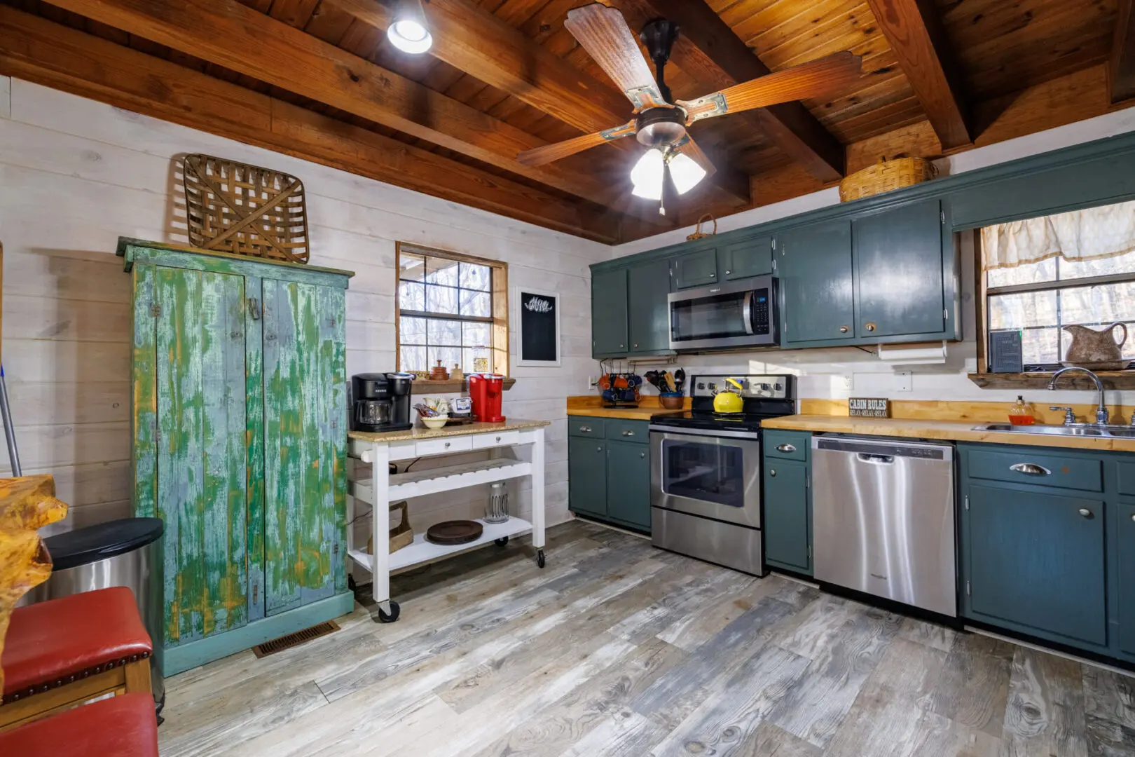 A vacation kitchen in a cabin with wood floors and a ceiling fan.