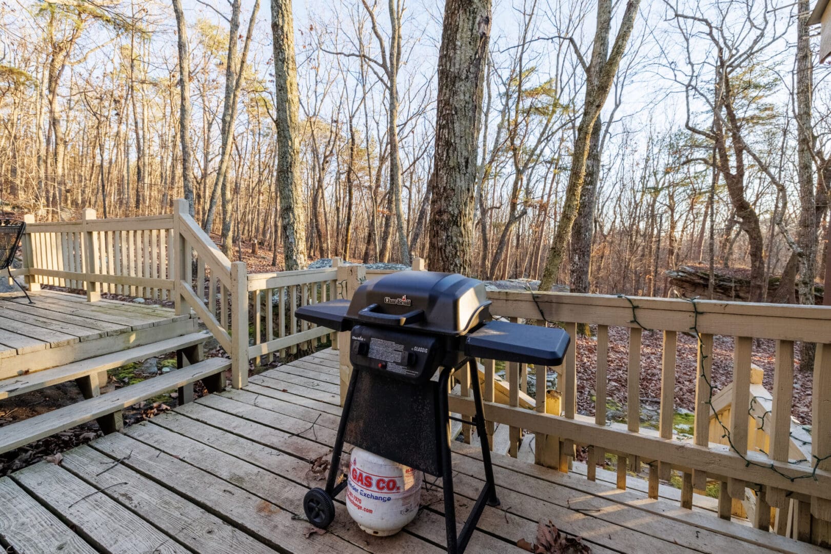 A vacation bbq grill on a deck in the woods.