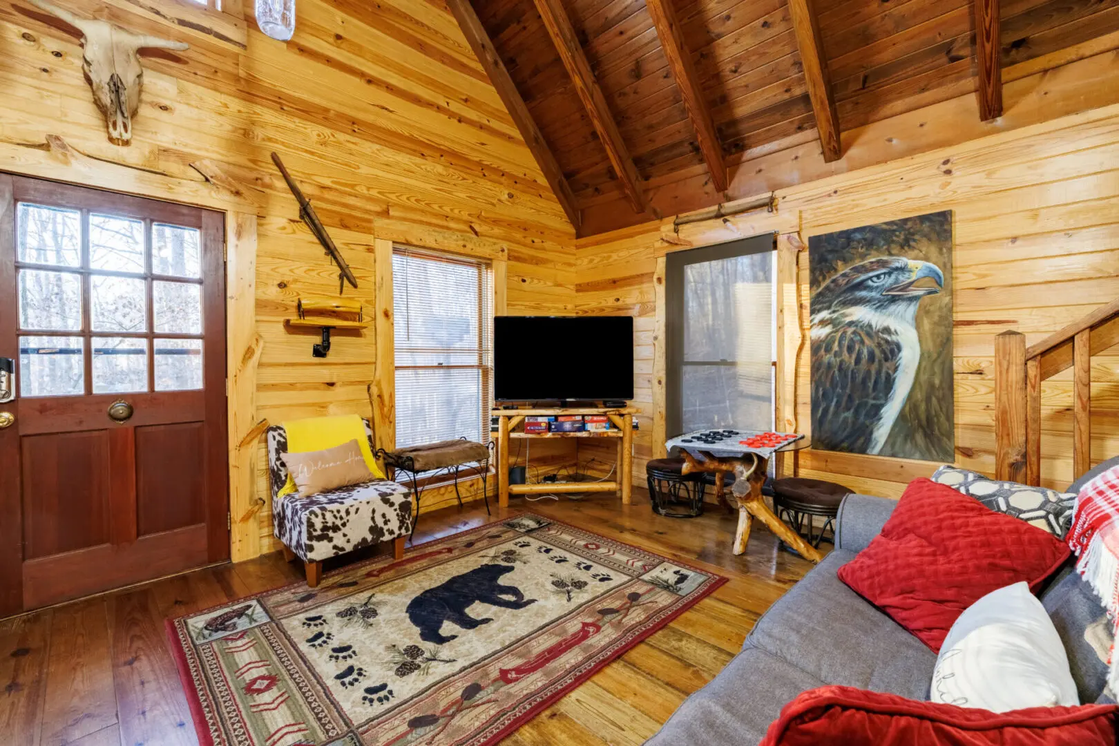 A cozy living room in a log cabin with a TV, perfect for a vacation getaway.
