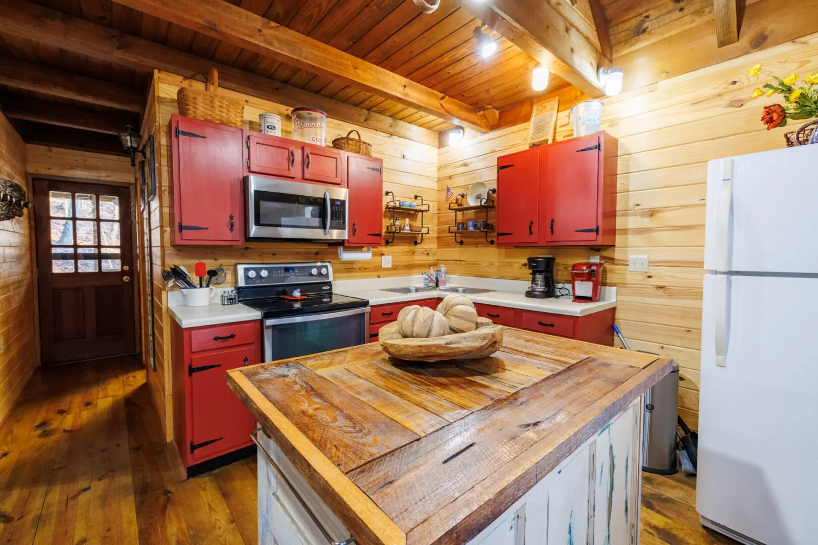 A rustic log cabin kitchen with red cabinets, perfect for a cozy vacation getaway.