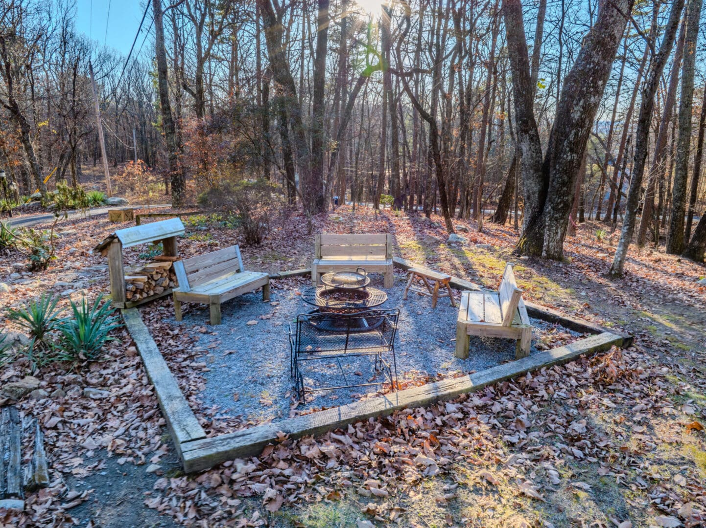 A tranquil fire pit nestled in the midst of a serene wooded area, offering the perfect ambiance for a peaceful vacation retreat.