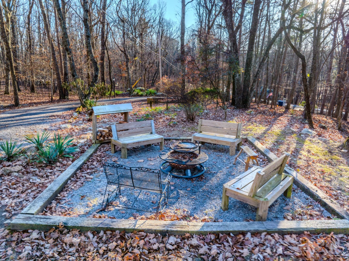 A vacation spot featuring a fire pit nestled amidst trees and wood benches.