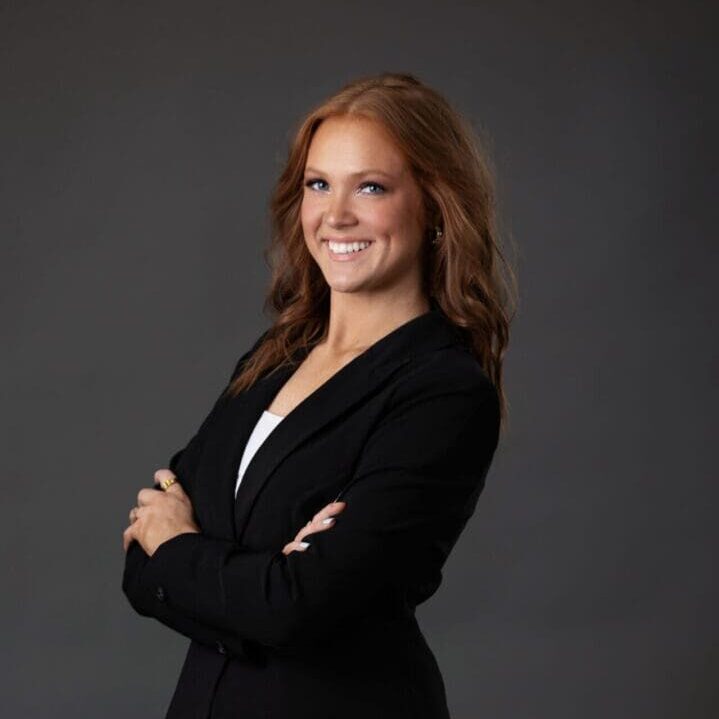 A business woman in a black suit posing for a photo.